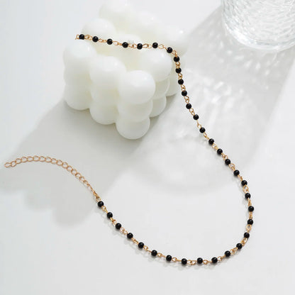 Bead Necklace Women in Black With Candle Beside it