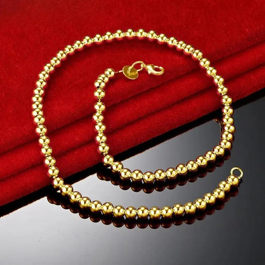 Gold Beaded Necklace on a red satin and glossy black background 