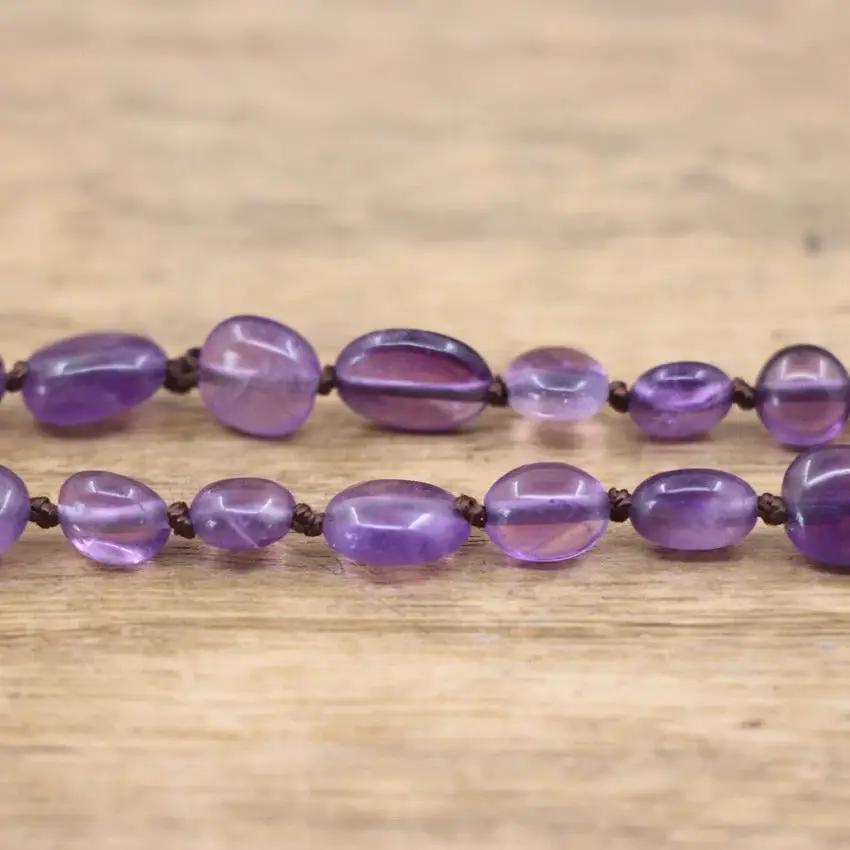 Purple quartz beads from the Purple Gemstone Necklace on a wooden background